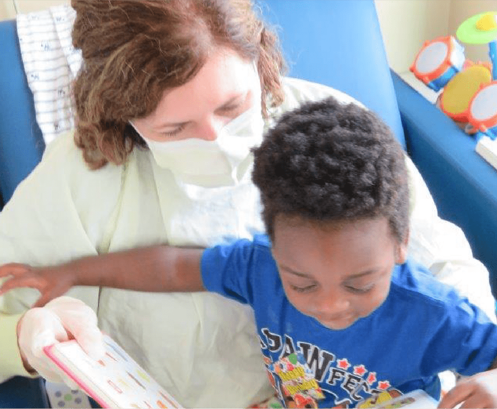 Little boy being read to in the hospital by health care professional