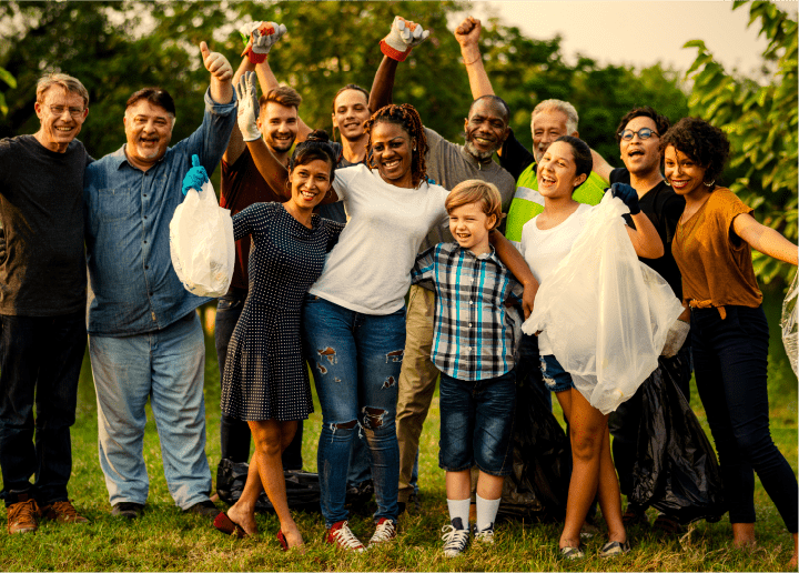 Diverse group of people of all ages celebrating after working together to clean up outside